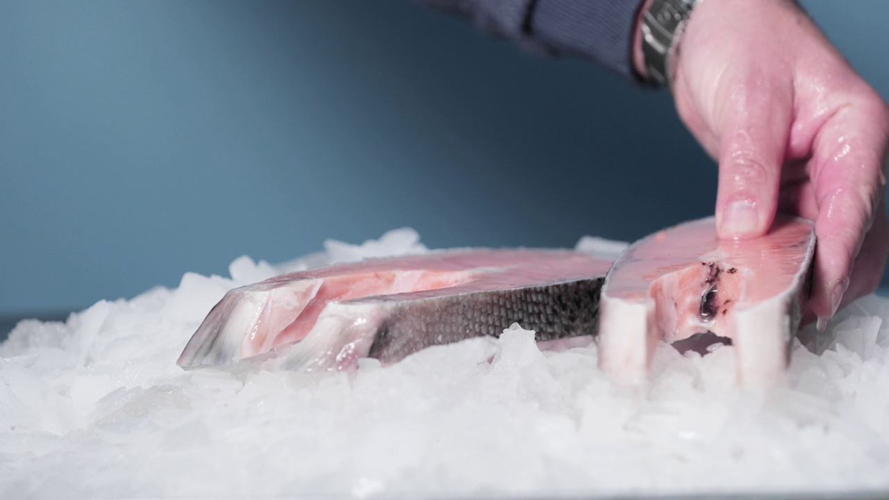 鱼贩的手把切好的鲑鱼放在冰上视频下载