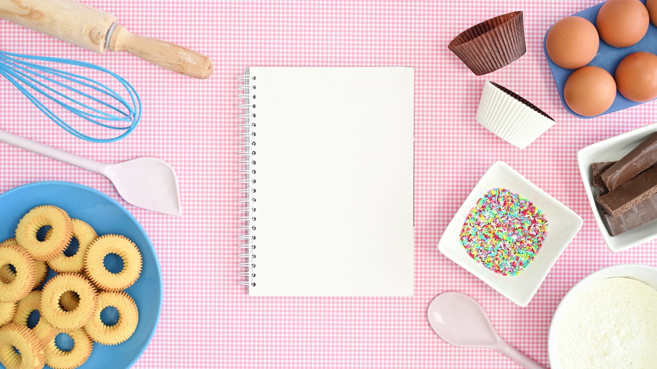 烤食材和饼干在盘子上出现在淡粉色的背景上，空白的笔记本上的食谱。止动平铺视频下载