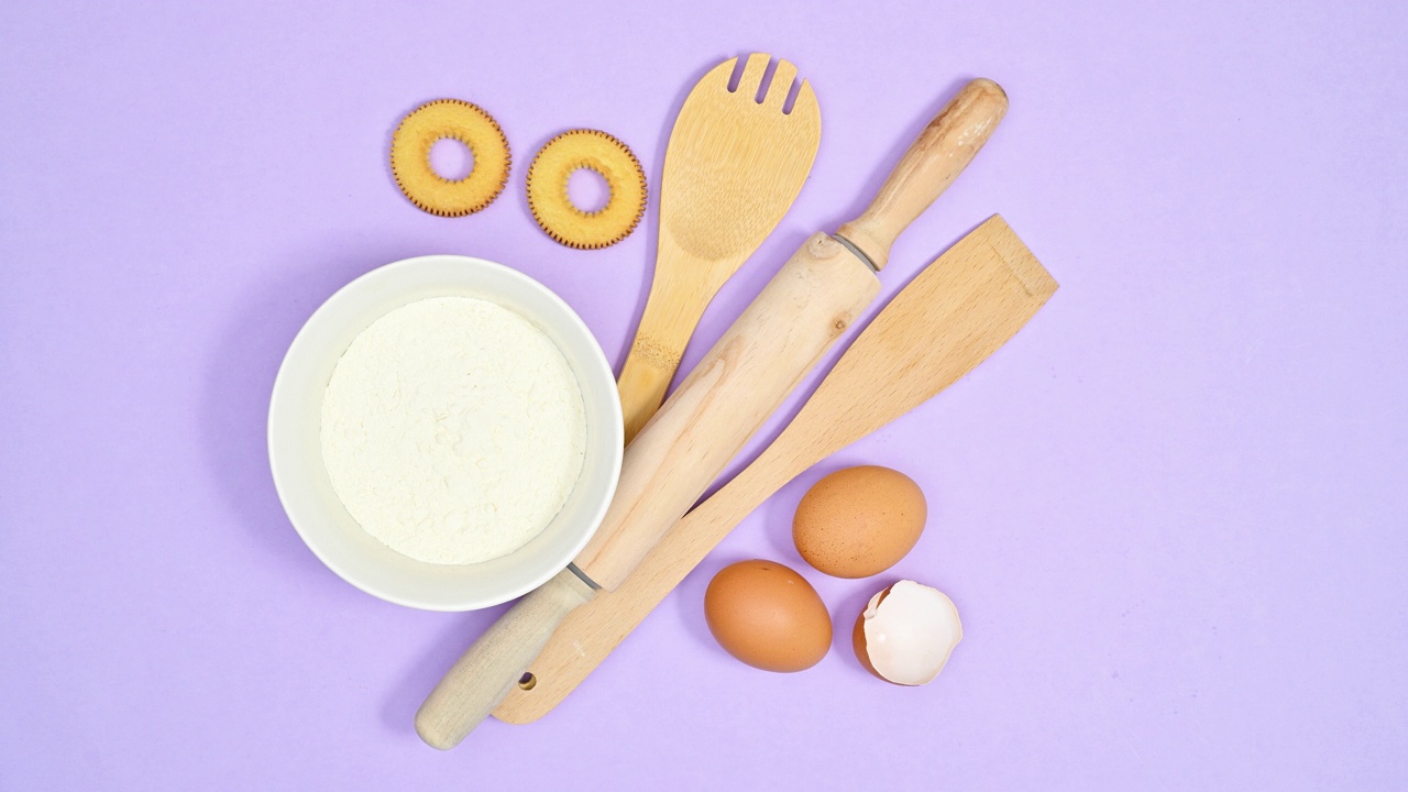 木制烘焙厨房工具面粉和鸡蛋出现在紫色主题上，用于制作饼干。止动平铺视频下载