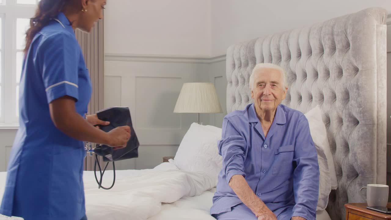 在家中卧床的老年男子，由穿制服的女护理人员测量血压视频素材