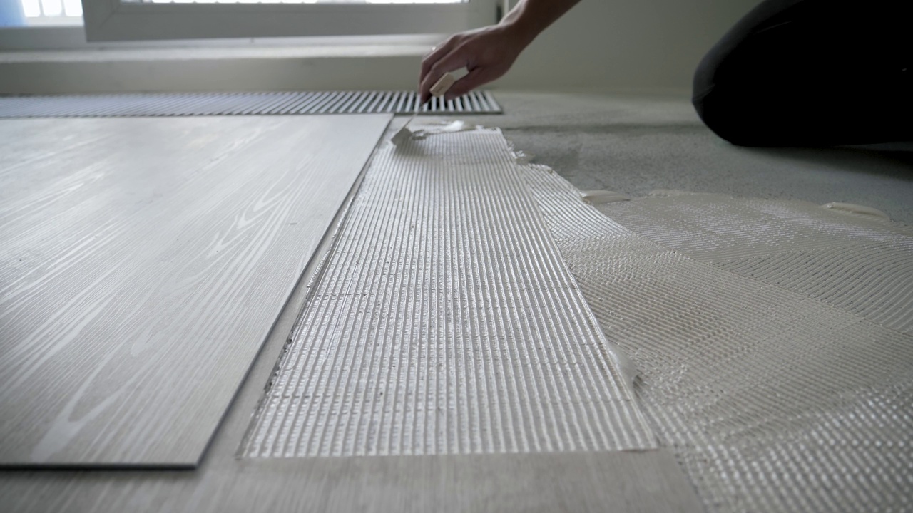 工人在涂胶乙烯基或层压板之前用刮刀在地板上涂上胶水视频素材
