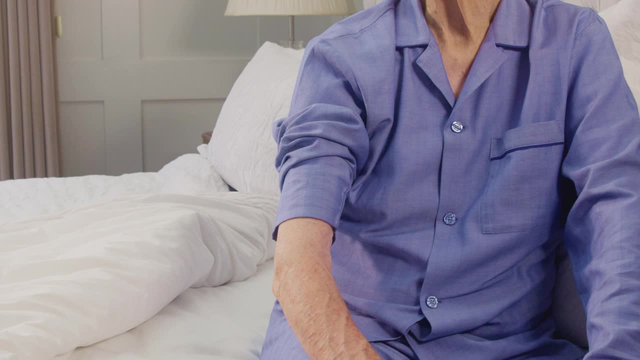 老年男子在家里的床上被穿着制服的女护工测量血压的特写视频素材