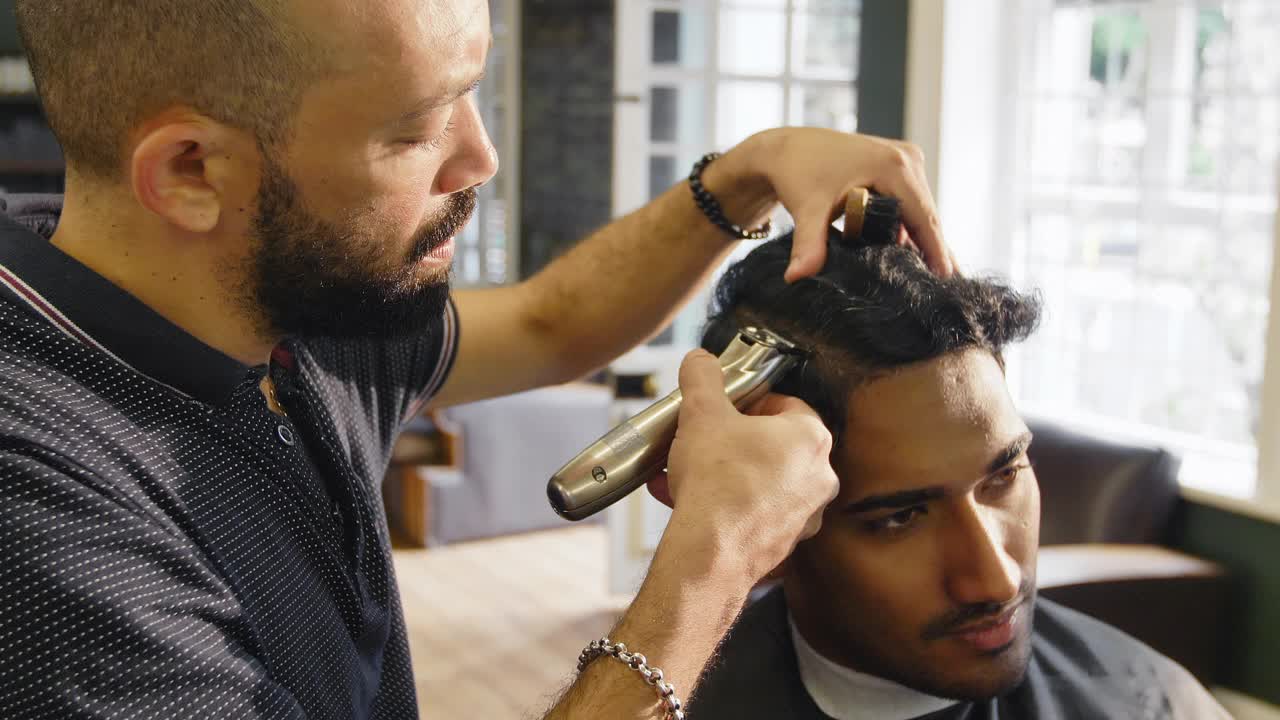 理发师在理发店用电动剃须刀剃男人的头发视频下载