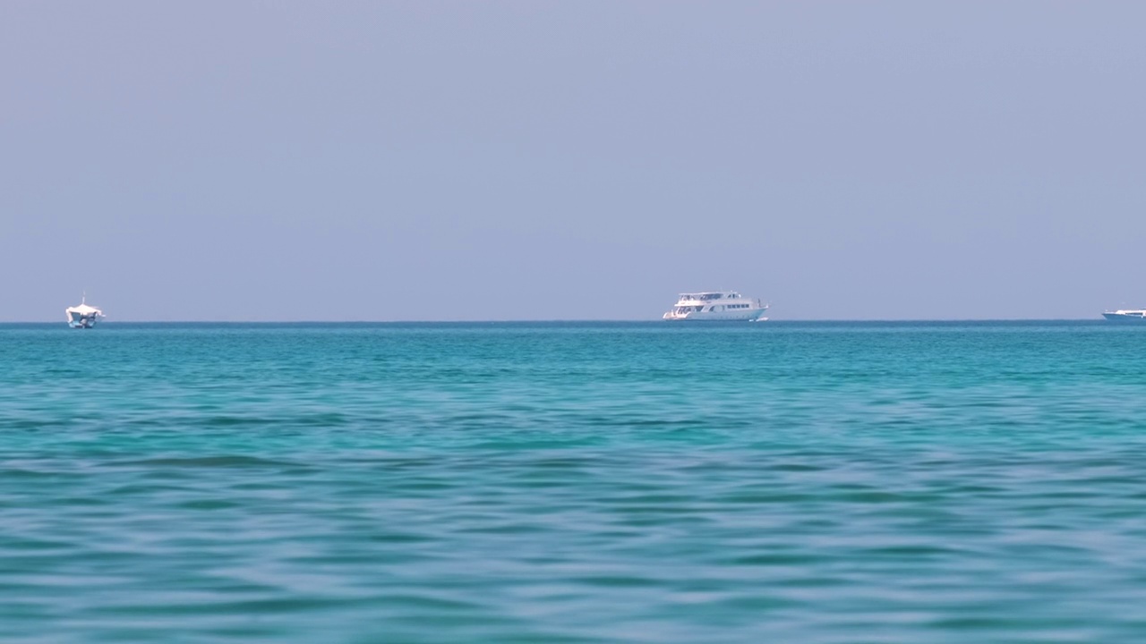 蔚蓝的海水泛起涟漪，远处的船只在平静的波浪上漂浮视频素材