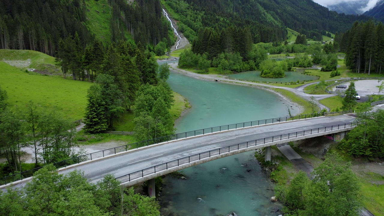 鸟瞰一辆汽车在桥上行驶，背景是蓝色的河水和瀑布。奥地利蒂罗尔州视频素材