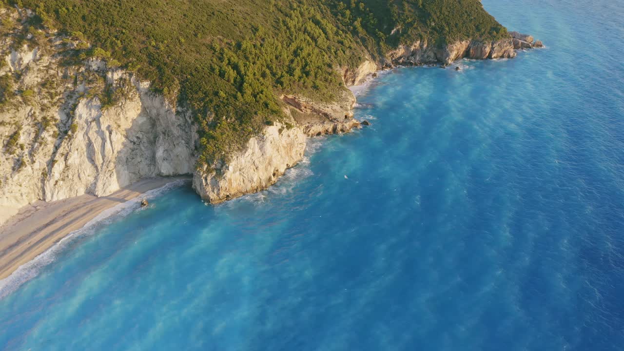 鸟瞰希腊爱奥尼亚岛莱夫卡达美丽的米洛斯海滩。日落金色的阳光，悬崖般的海岸线和原始的海浪打破了蓝绿色的大海在岸边视频下载