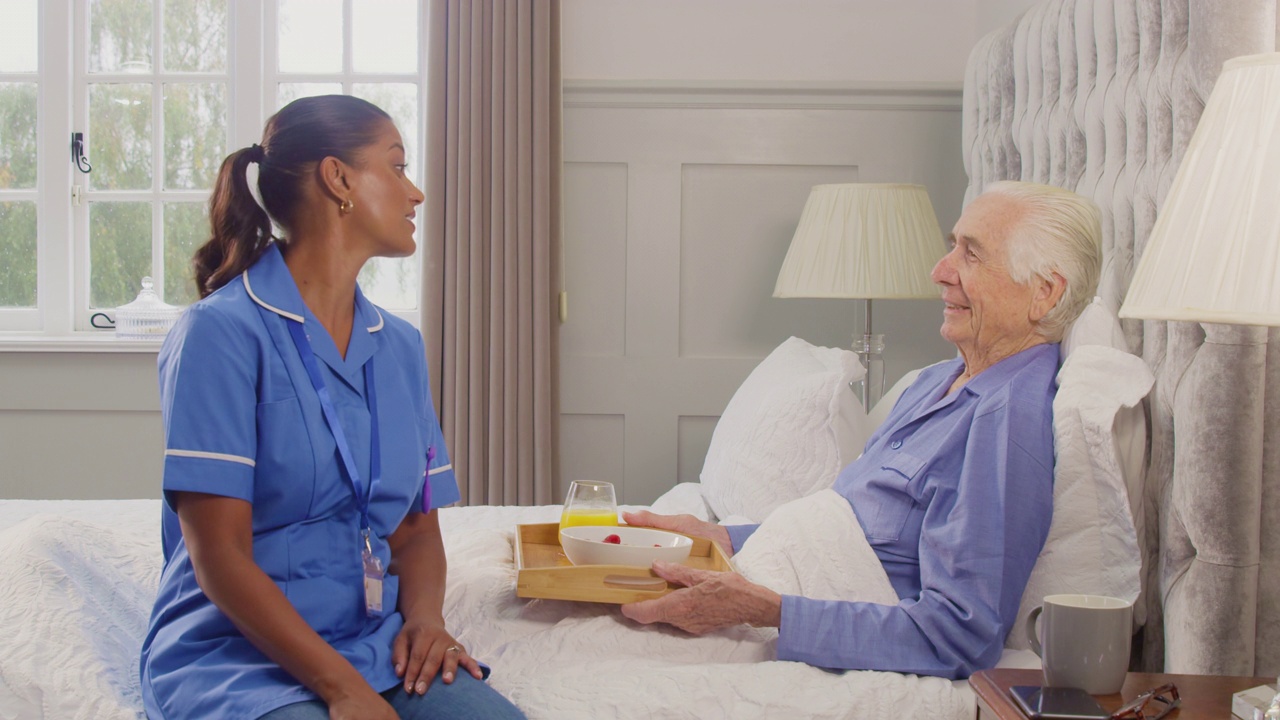 穿着制服的女护工将早餐放在床上送老人回家视频下载