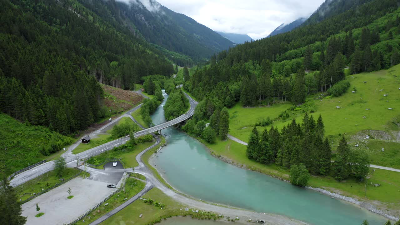 空中镜头的山路穿越蓝色河流在美丽的紫色森林和瀑布的背景。奥地利蒂罗尔州视频素材