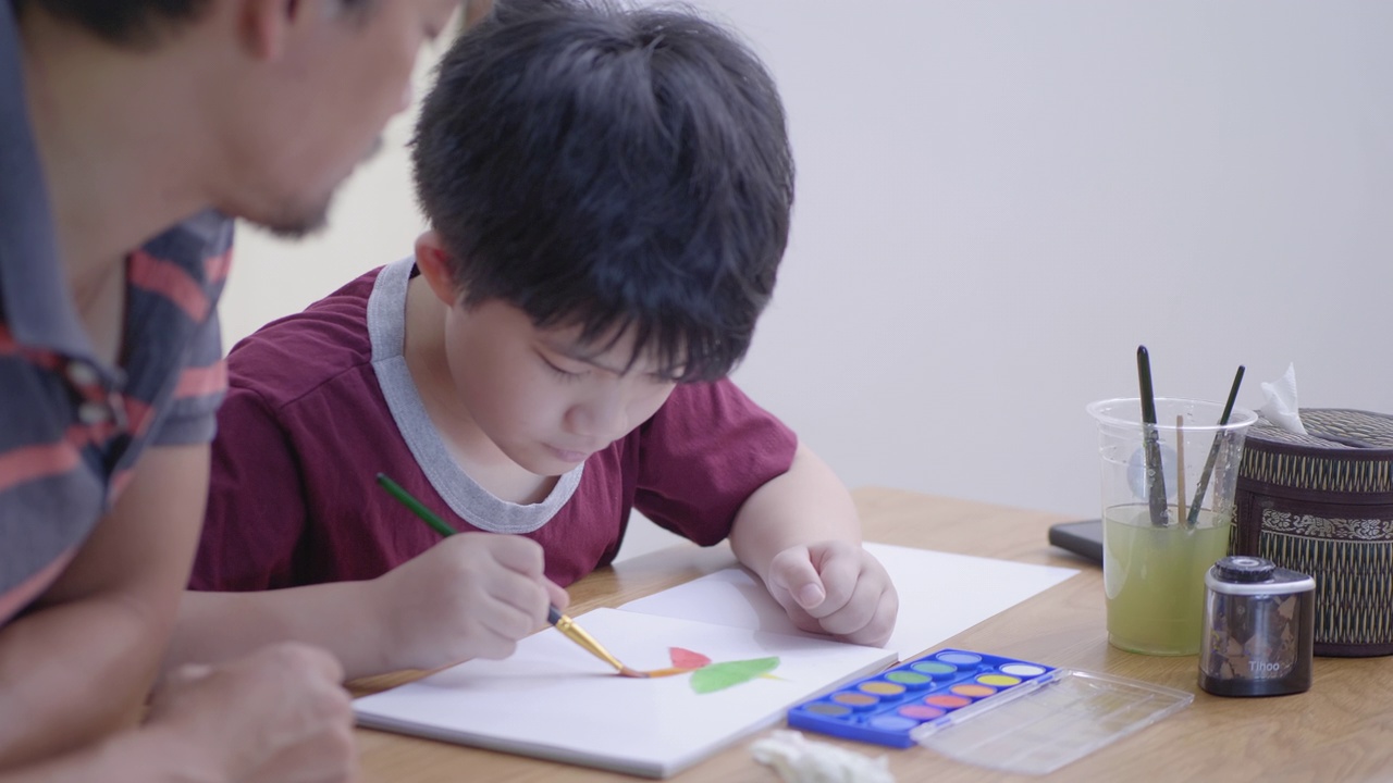 亚洲男孩和父亲在家里画水彩画视频下载