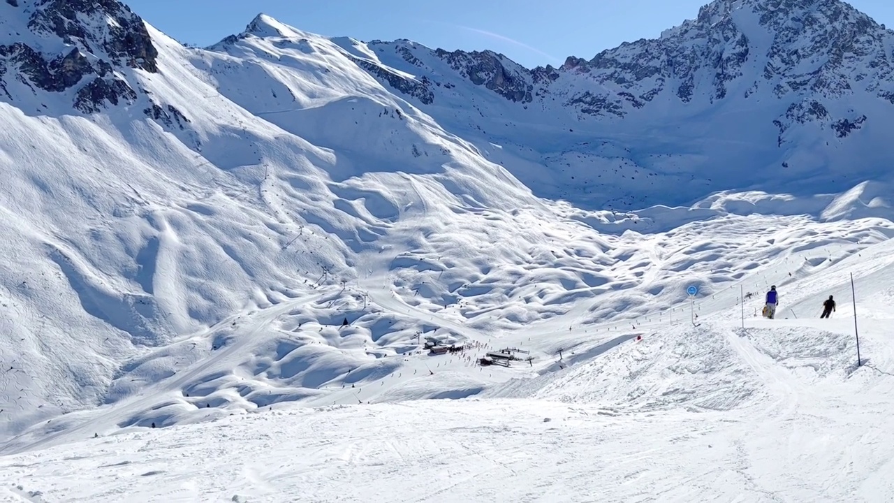 人们在著名的滑雪胜地Courchevel宽阔的斜坡上滑雪。视频下载