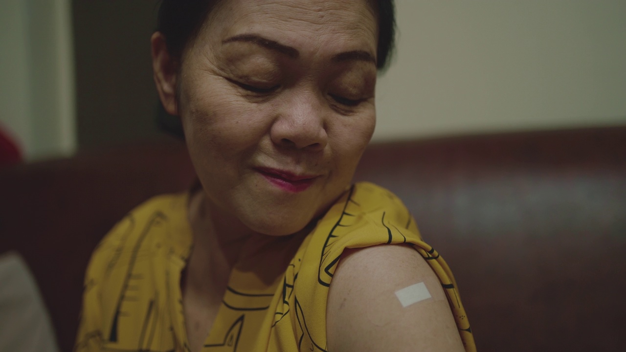 一位刚打过疫苗的老妇人在展示她的手臂。视频下载