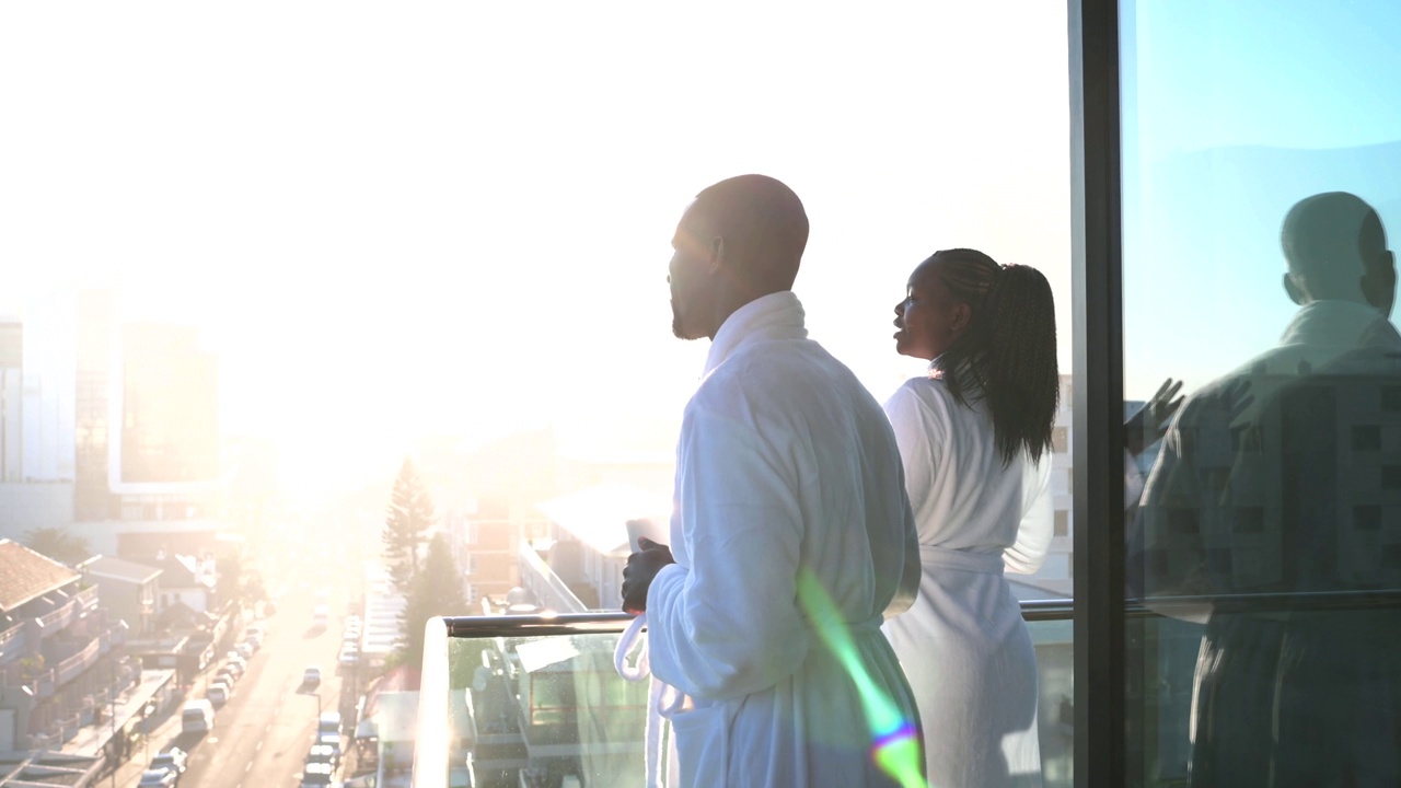 一对非洲夫妇穿着浴袍在日出时俯瞰美丽的城市景观视频下载