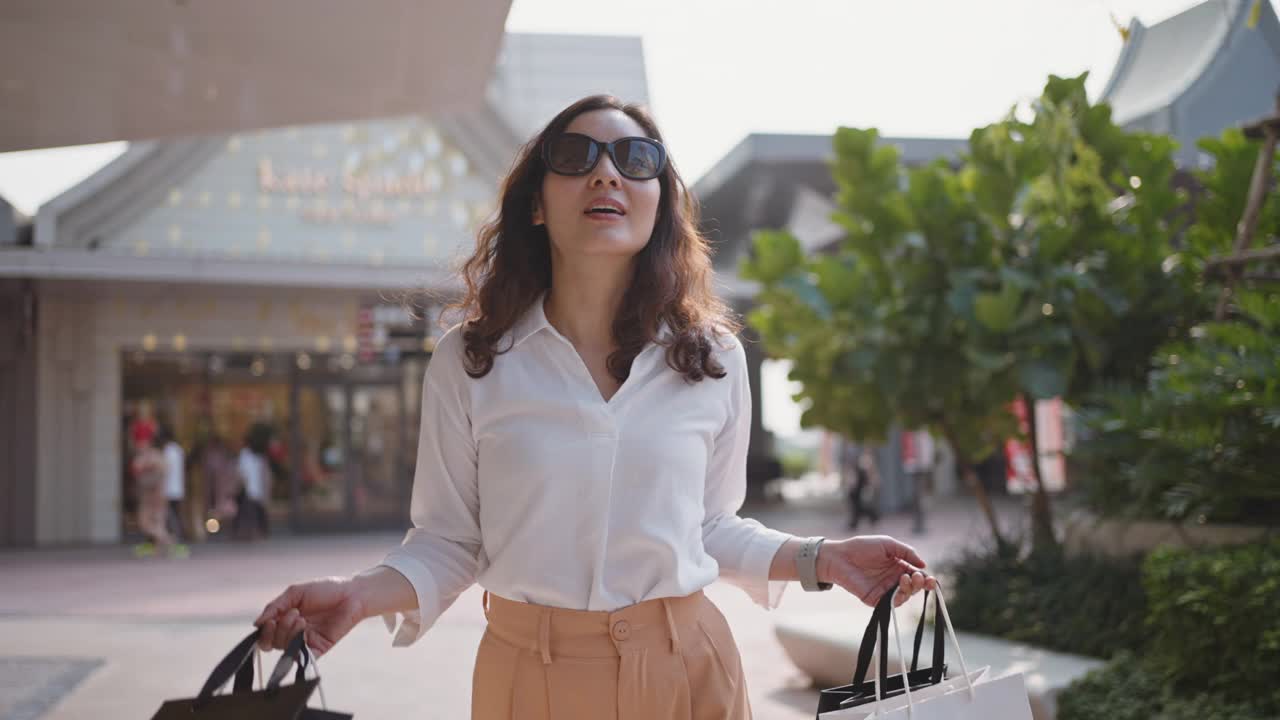 亚洲妇女购物者步行与购物袋视频素材