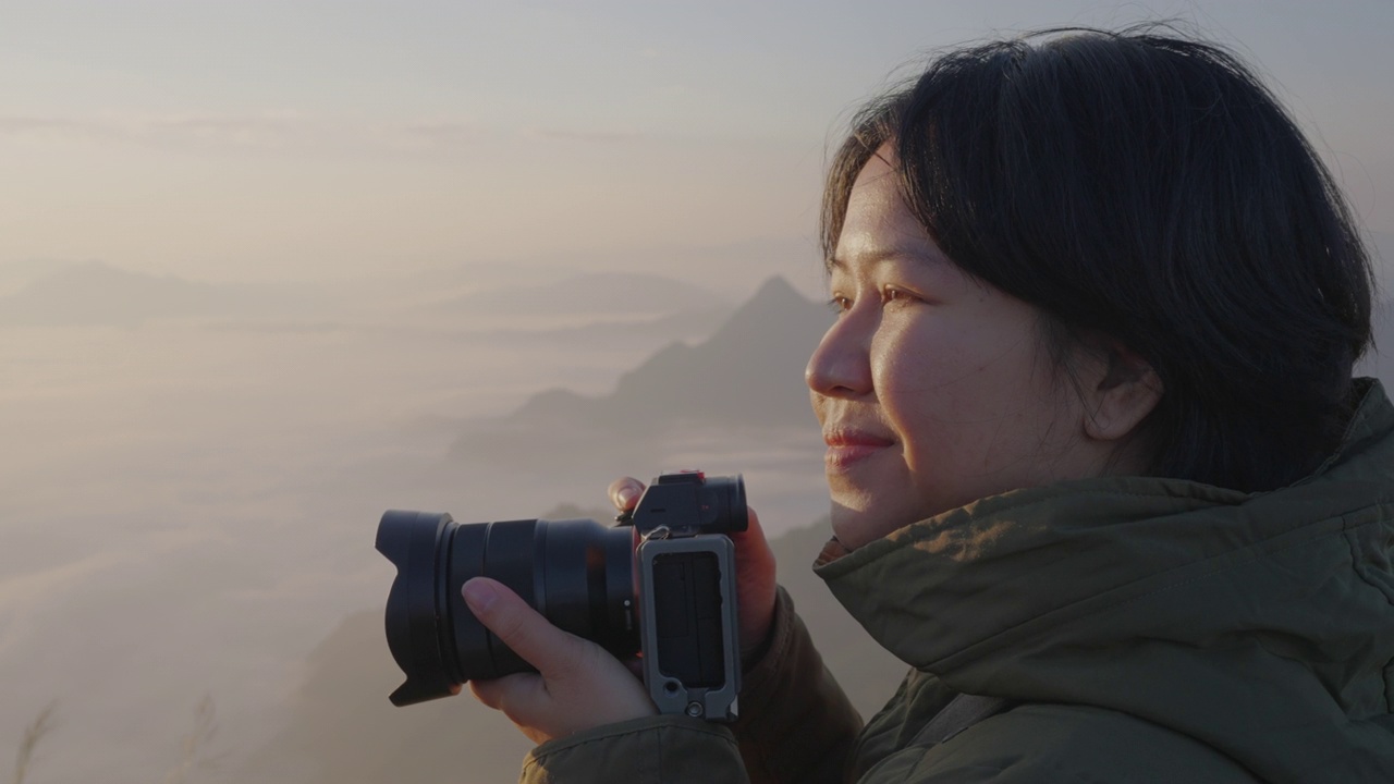 女背包客在摄影之旅中悠闲地捕捉雾山的形象。视频素材