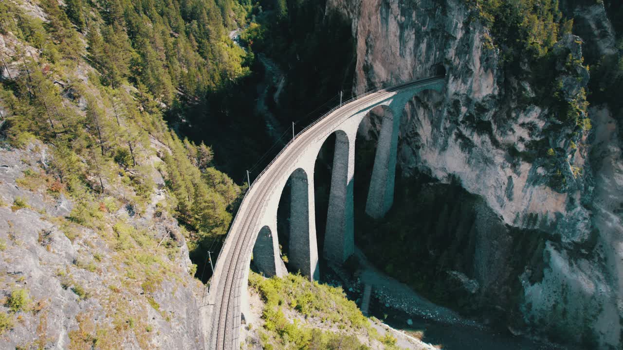 一列红色列车在瑞士阿尔卑斯山的Landwasser高架桥上行驶的鸟瞰图视频下载