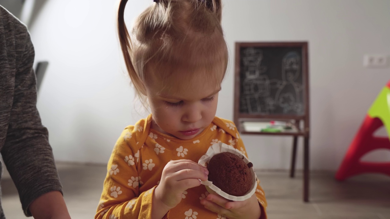可爱的小女孩在家吃松饼，特写镜头。小女孩胃口大开地吃着蛋糕。视频素材