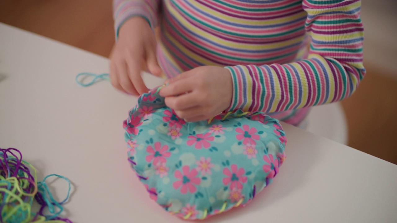 年轻女孩在家里用塑料针和纱线缝制衬垫工艺视频下载
