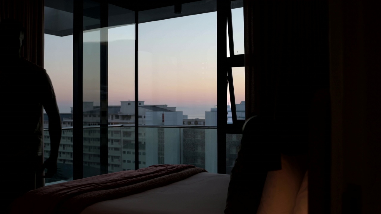 在高层公寓的床上拍摄的一个年轻人伸展准备去晨跑。视频下载