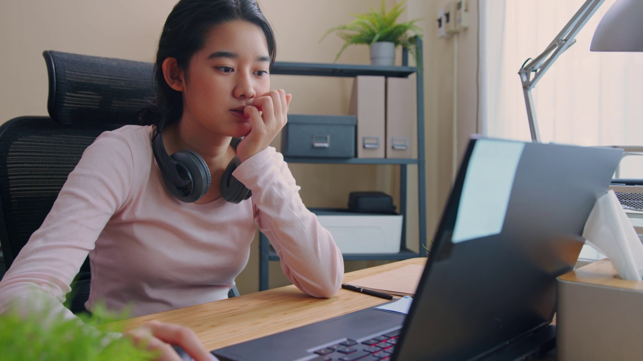 十几岁的女孩用笔记本电脑在家里上网找工作或兼职。视频下载