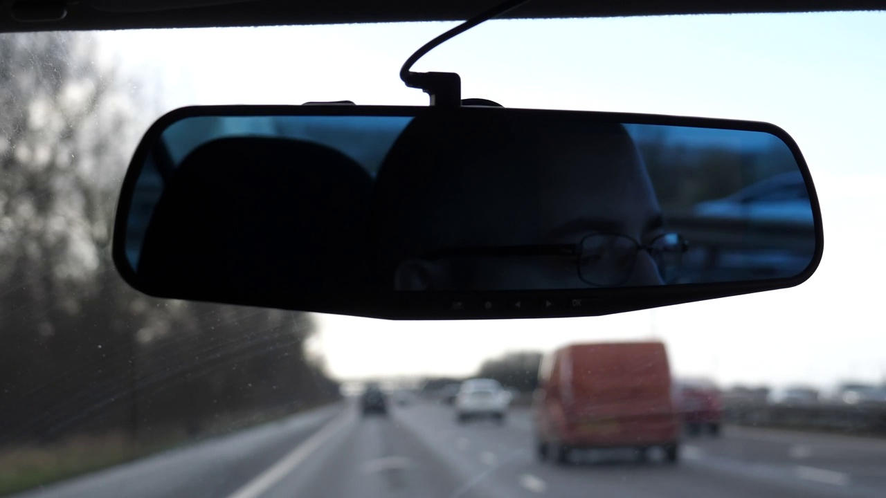 司机的脸在镜子里，高速公路模糊不清。视频下载