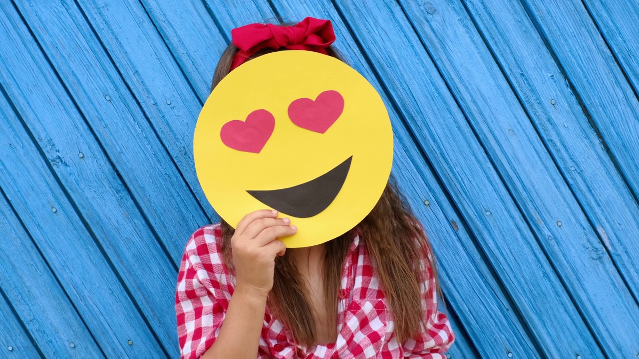卷发可爱的女孩把表情符号从恋人变成了微笑的人。视频素材