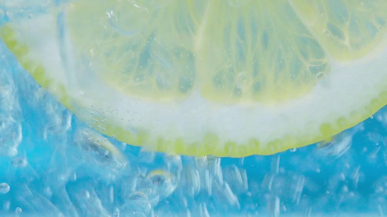 柠檬片的水下特写，蓝色背景上的气泡。有选择性的重点视频素材