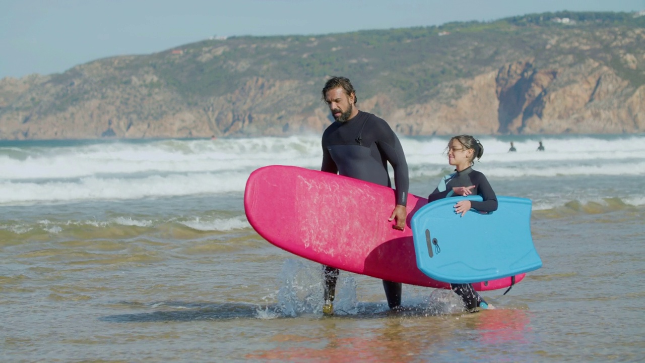 前视图冲浪教练与残疾和孩子进入海洋视频下载