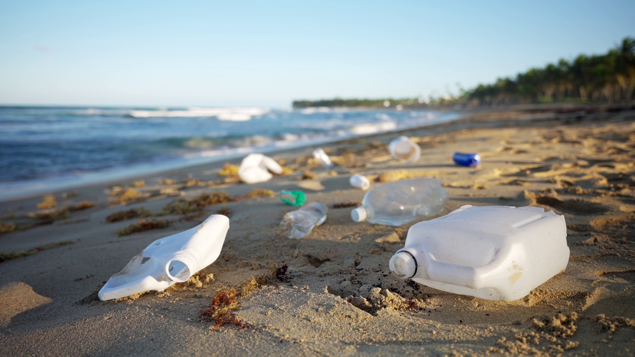 肮脏的热带海滩。夕阳下沙滩上的塑料瓶。视频素材
