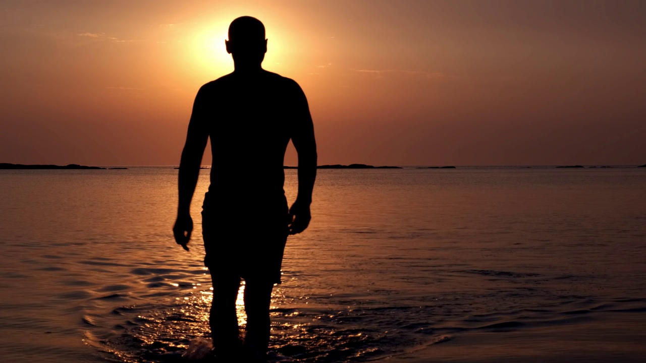 在落日的余晖中，一个肌肉发达的男人的轮廓出现在海面上。度假，旅行，自由，健身视频下载
