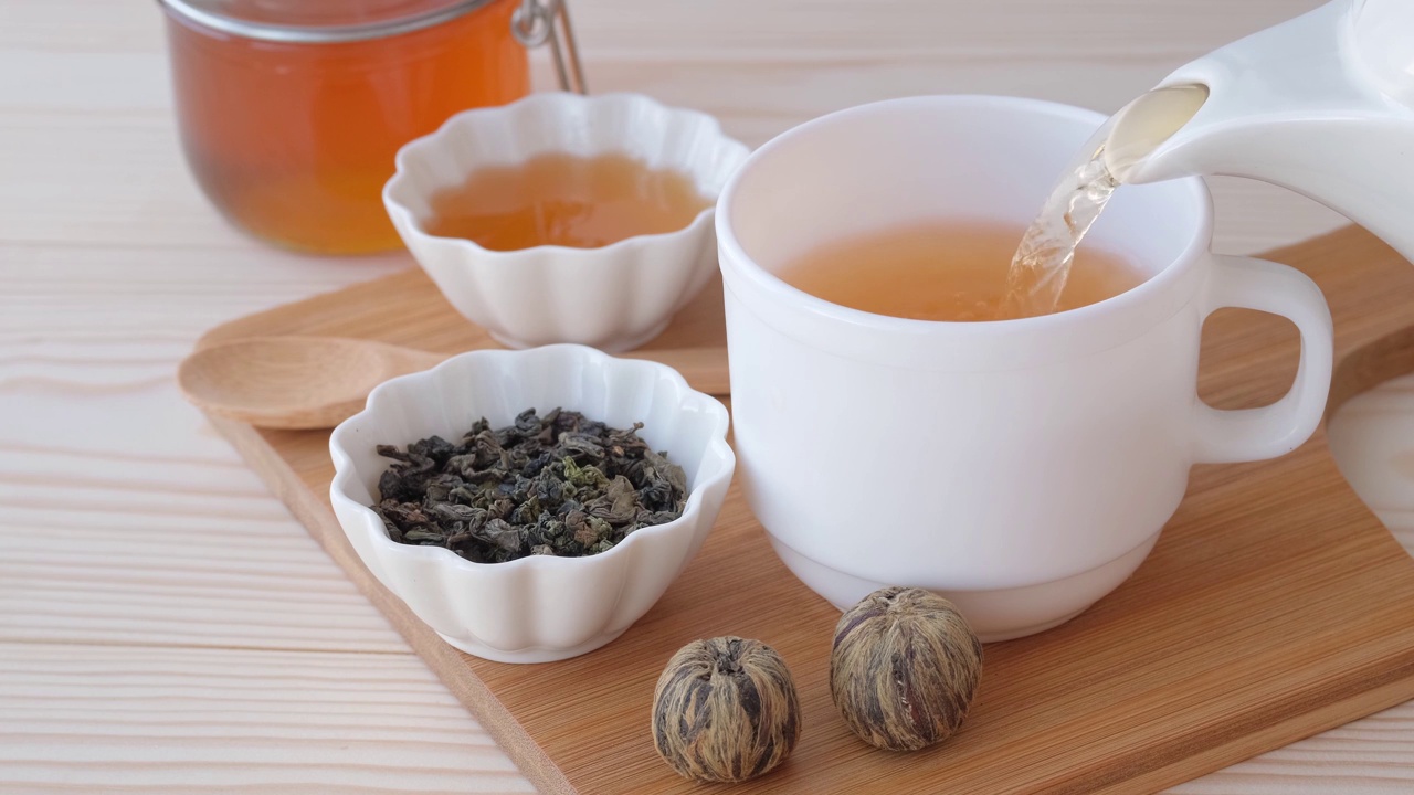 两种绿茶在木桌的背景上，蜂蜜和一个白色的杯子倒着茶。健康饮食的概念。视频下载