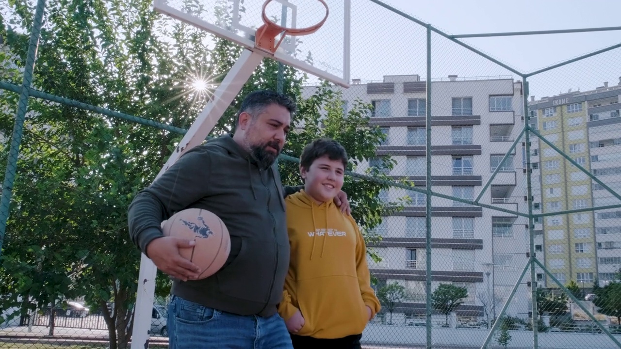 父亲和儿子在户外篮球场玩得很开心视频下载