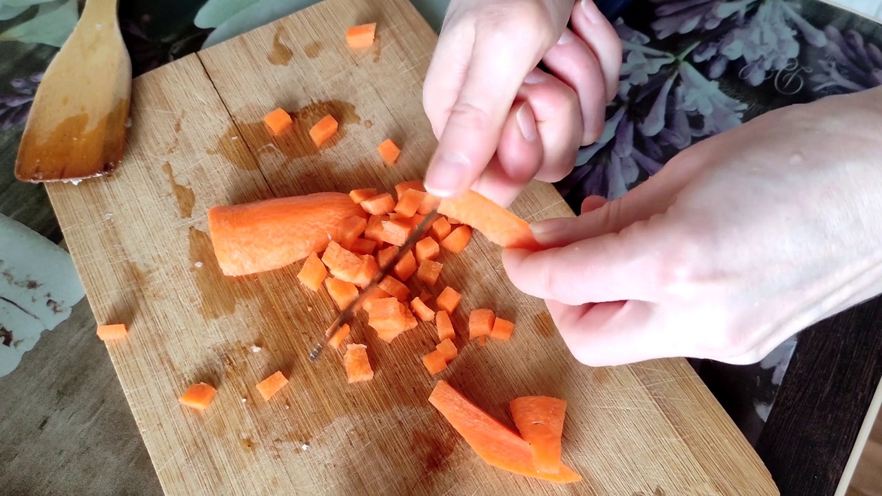 一个女人在砧板上切胡萝卜视频素材