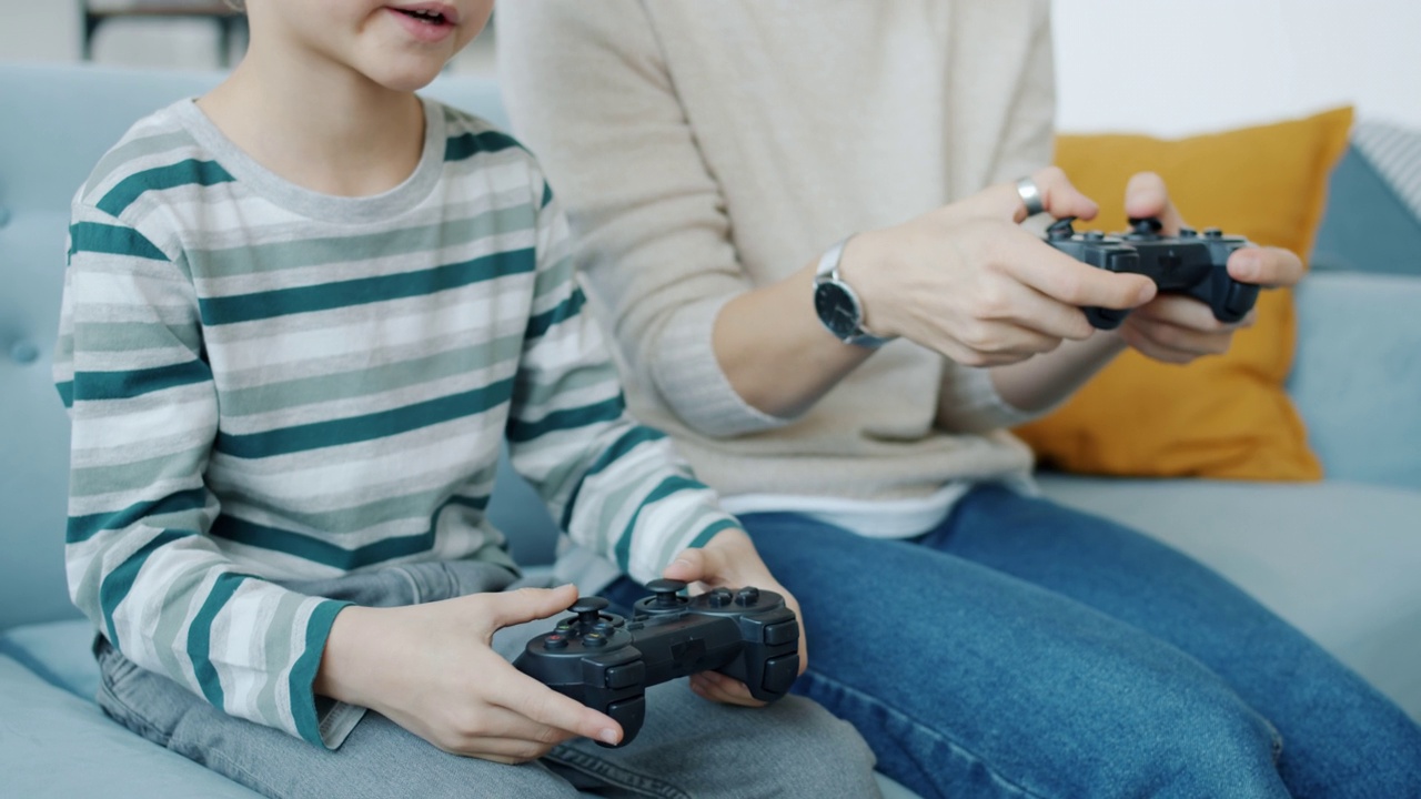 母亲和儿子在家里用操纵杆玩电子游戏，笑着击掌视频下载
