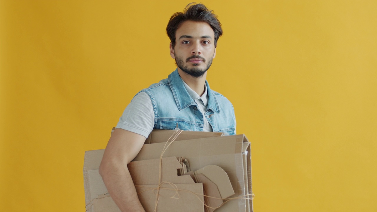 中东人的肖像，在黄色的背景上背着纸板进行回收视频下载