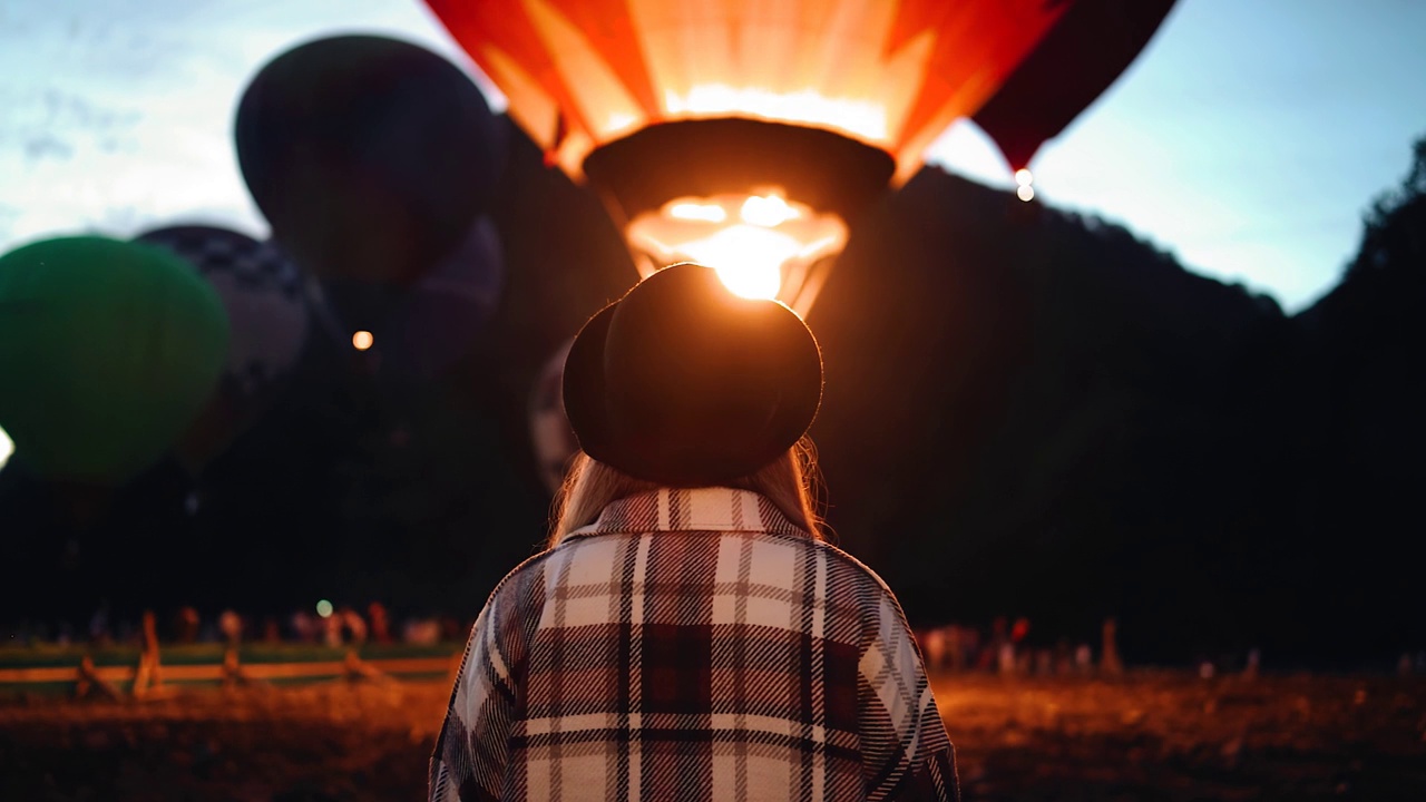 女孩站在一个气球上，这个气球在晚上开始上升到空中。夜间可见火光的闪光视频下载