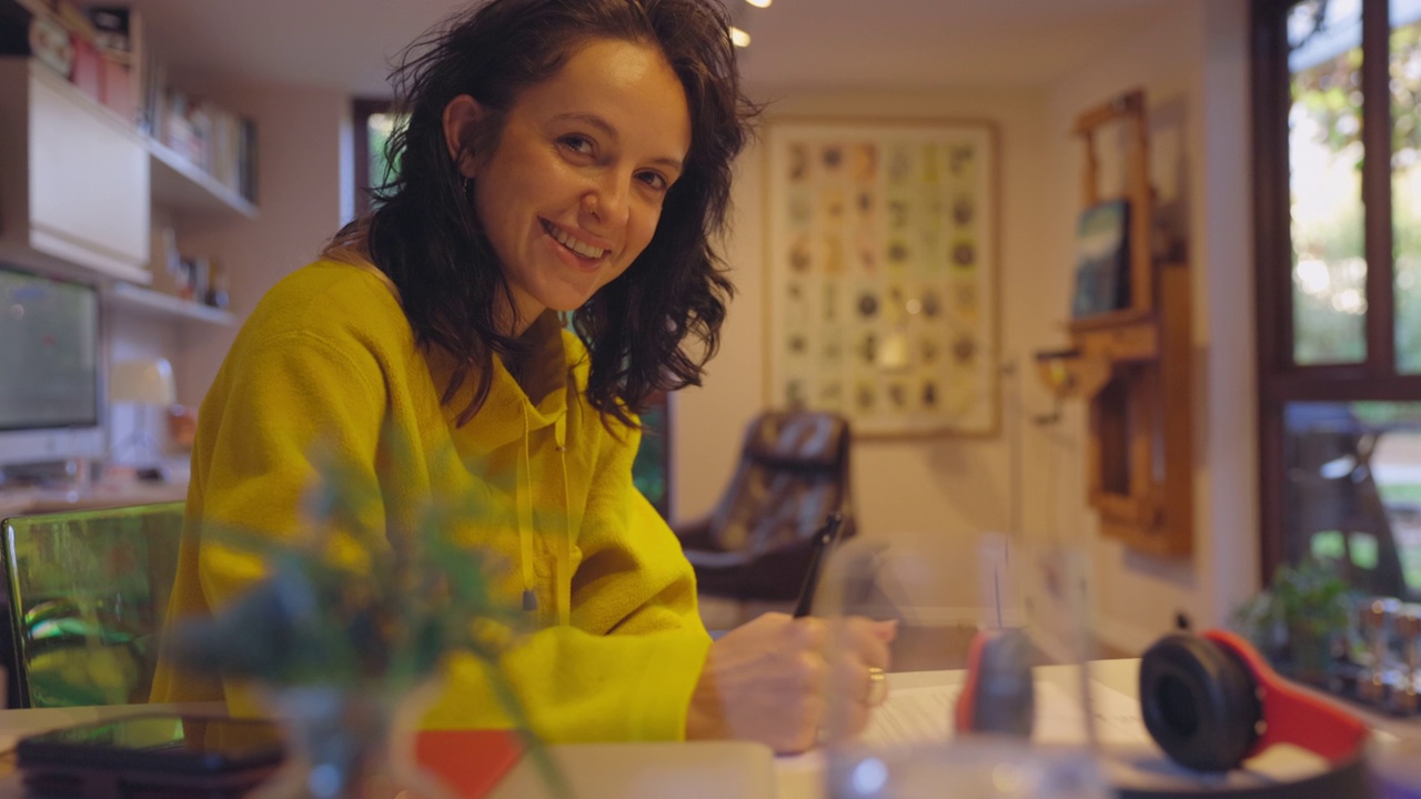 英国伦敦里士满，微笑的女士在家里的桌子上写作视频下载