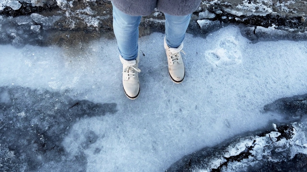 穿白靴子的女人踩在冰上，发出噼啪声视频素材