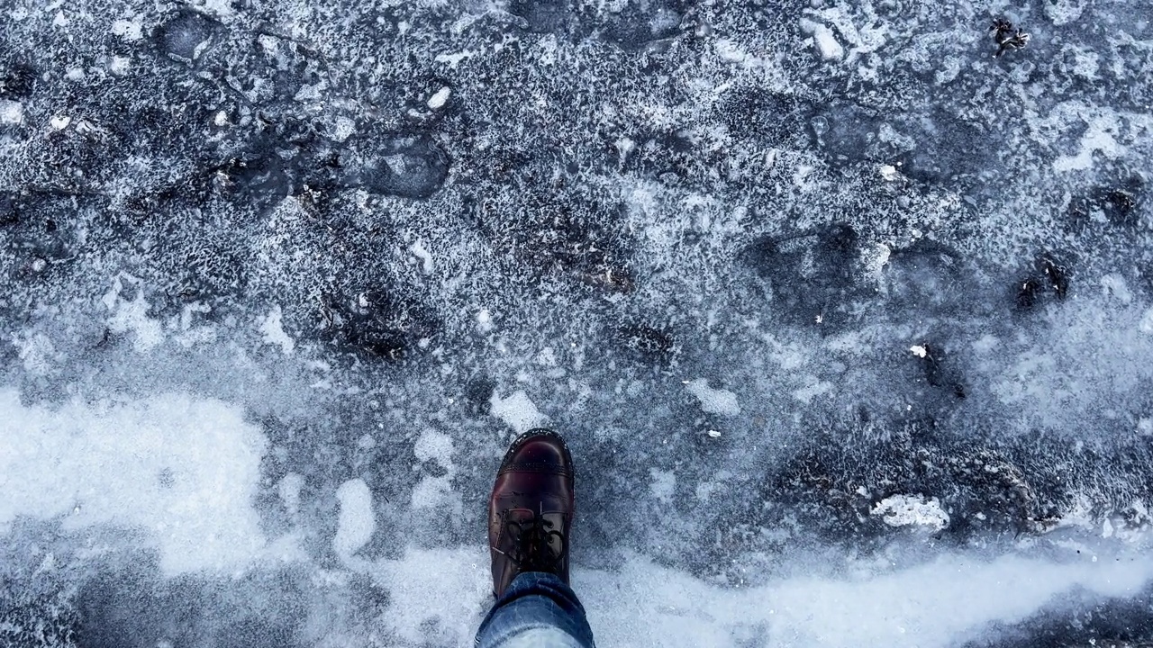 一名穿着靴子的男子踩在结冰的湖面上视频下载