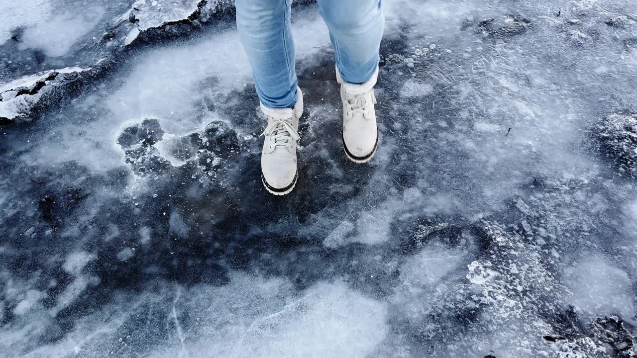 穿着白色靴子的年轻女子在玩冰踩冰，把冰弄裂视频素材