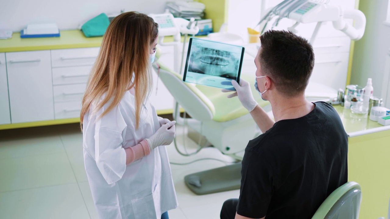 牙科诊所的同事通过分析病人的口腔全景x光图像进行交流。牙科医生和护士分析牙齿x光扫描视频素材