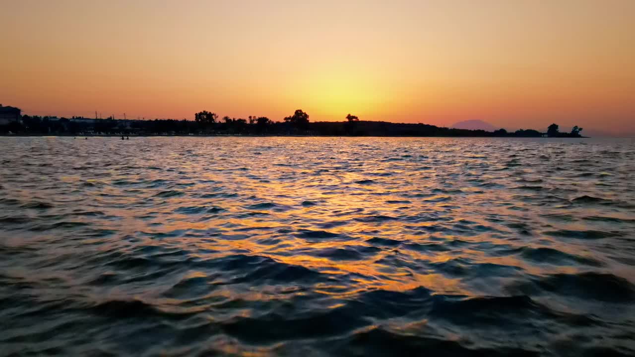 希腊爱奥尼亚海岸的日落。明亮的太阳，水面上的无人机，倒影。慢动作视频素材