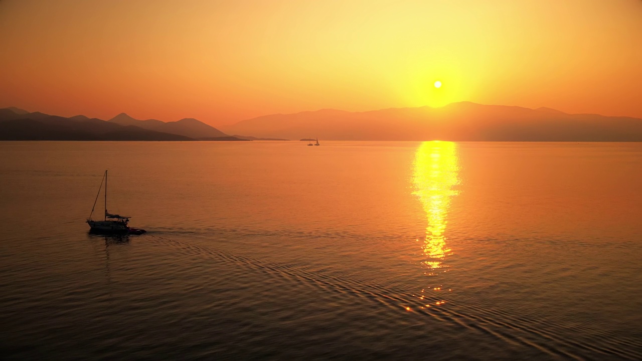 希腊爱奥尼亚海岸的日落。明亮的阳光，远处的陆地，漂浮的小船，水中的倒影视频素材