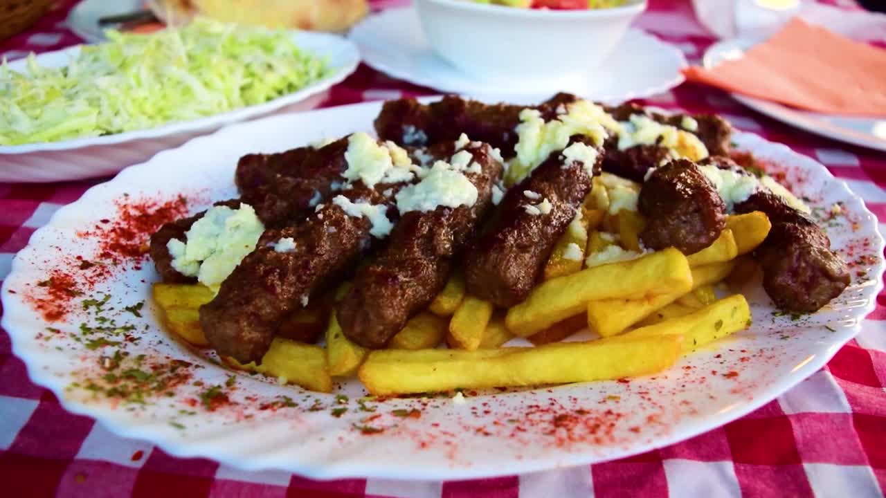 塞尔维亚的国菜蒸肉香肠(让人想起烤肉串的肉糜香肠)，背景是炸薯条和沙拉。视频下载