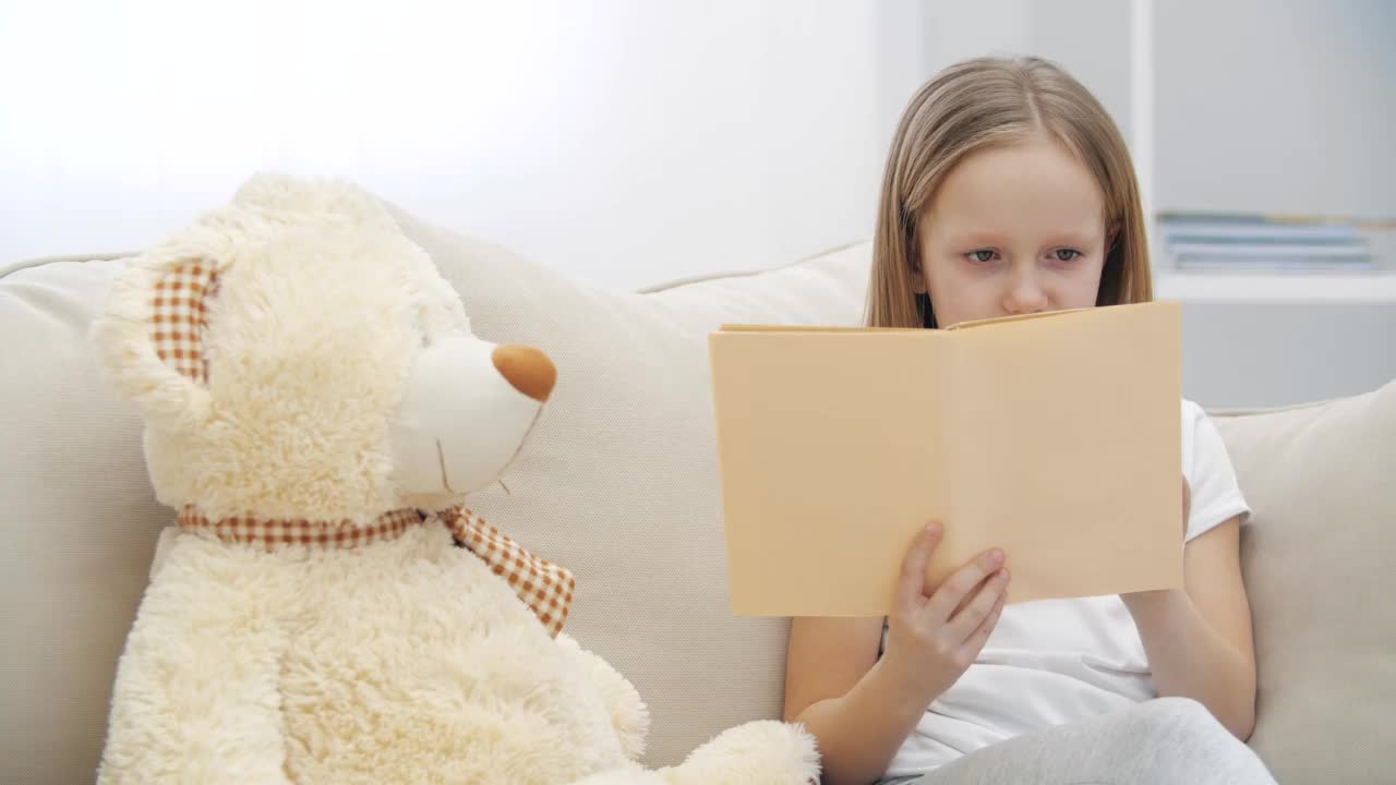 小女孩给她的泰迪熊读书的4k视频。视频素材