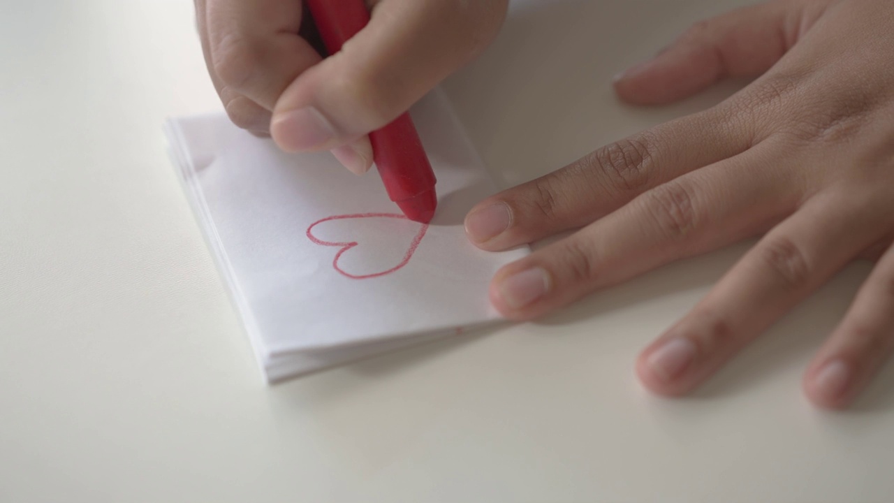 女人用蜡笔在白纸上画了一个红心的形状视频下载