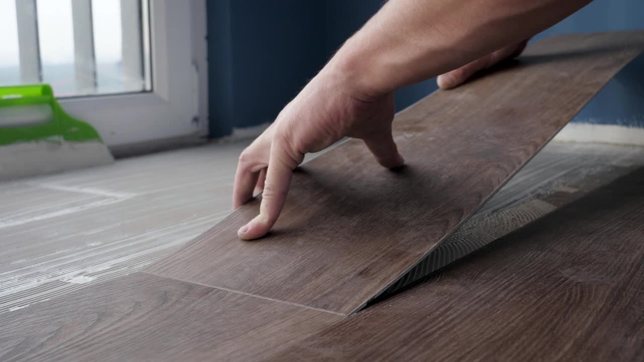 工人将一张乙烯基强化地板粘合到房子的地板上视频素材