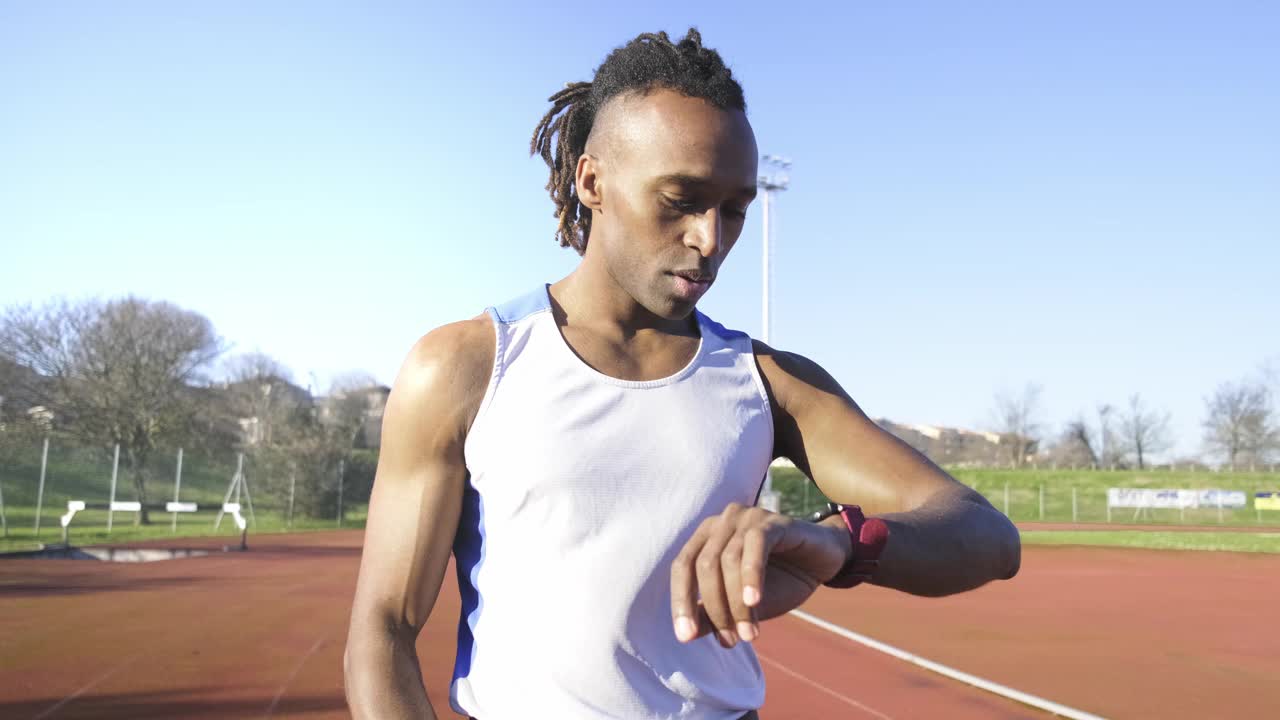 跑步者在跑道上看着运动智能手表，检查性能-运动和健身生活方式的概念视频下载