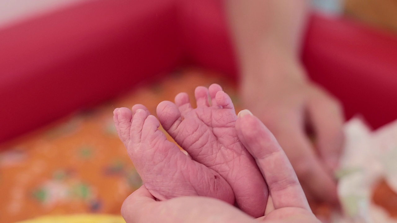 母亲的手握着刚出生的儿子的腿。视频下载
