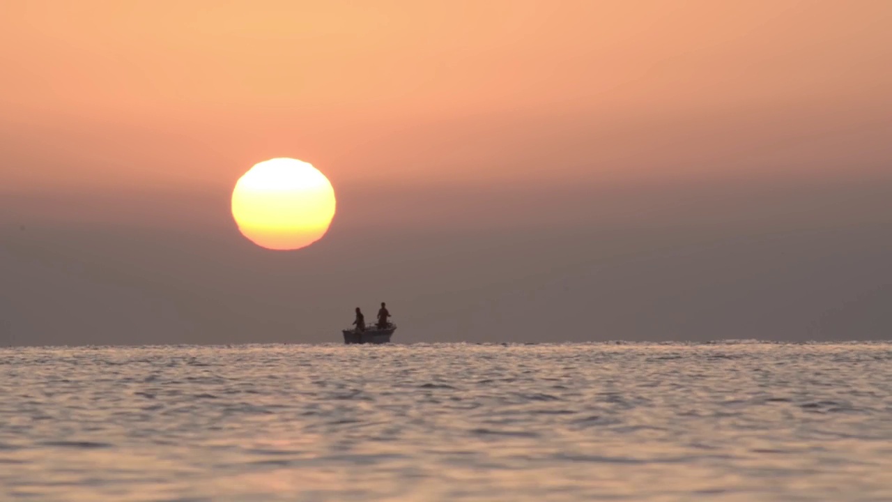 日出的海边，漂浮着几艘渔船视频素材