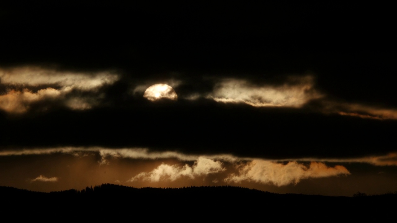 冉冉升起的太阳穿过云朵，云朵在山林中高速移动视频素材